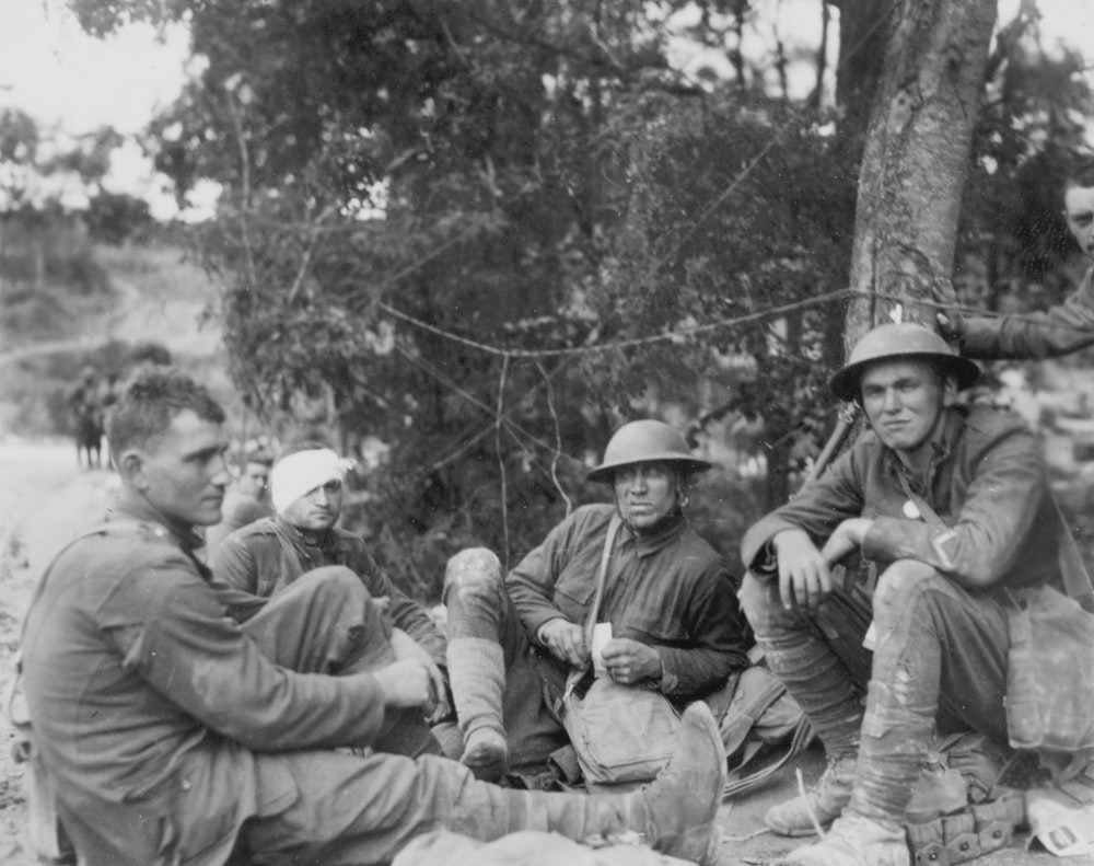 Soldados aliados, um com a cabeça enfaixada, sentados no chão durante a Primeira Guerra Mundial