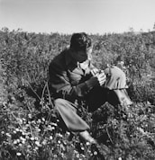 A metal detectorist carefully scanning a field, with a focus on their attentive posture and the vast landscape around them.