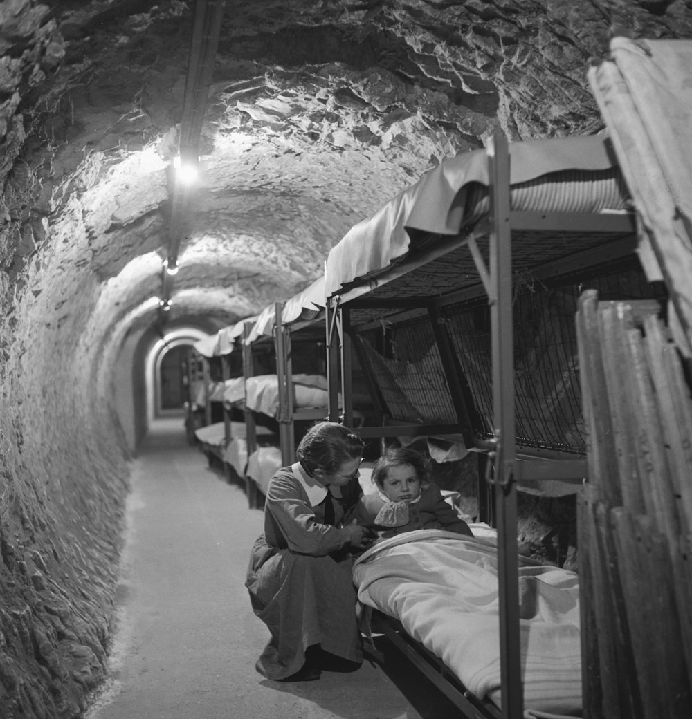第2次世界大戦中のロンドン爆撃の地下トンネルで、子供のベッドの隣にひざまずく女性