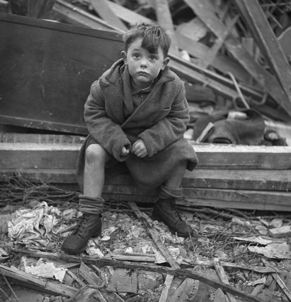 Boy seated in wreckage of building after a bombing raid of London during World War II