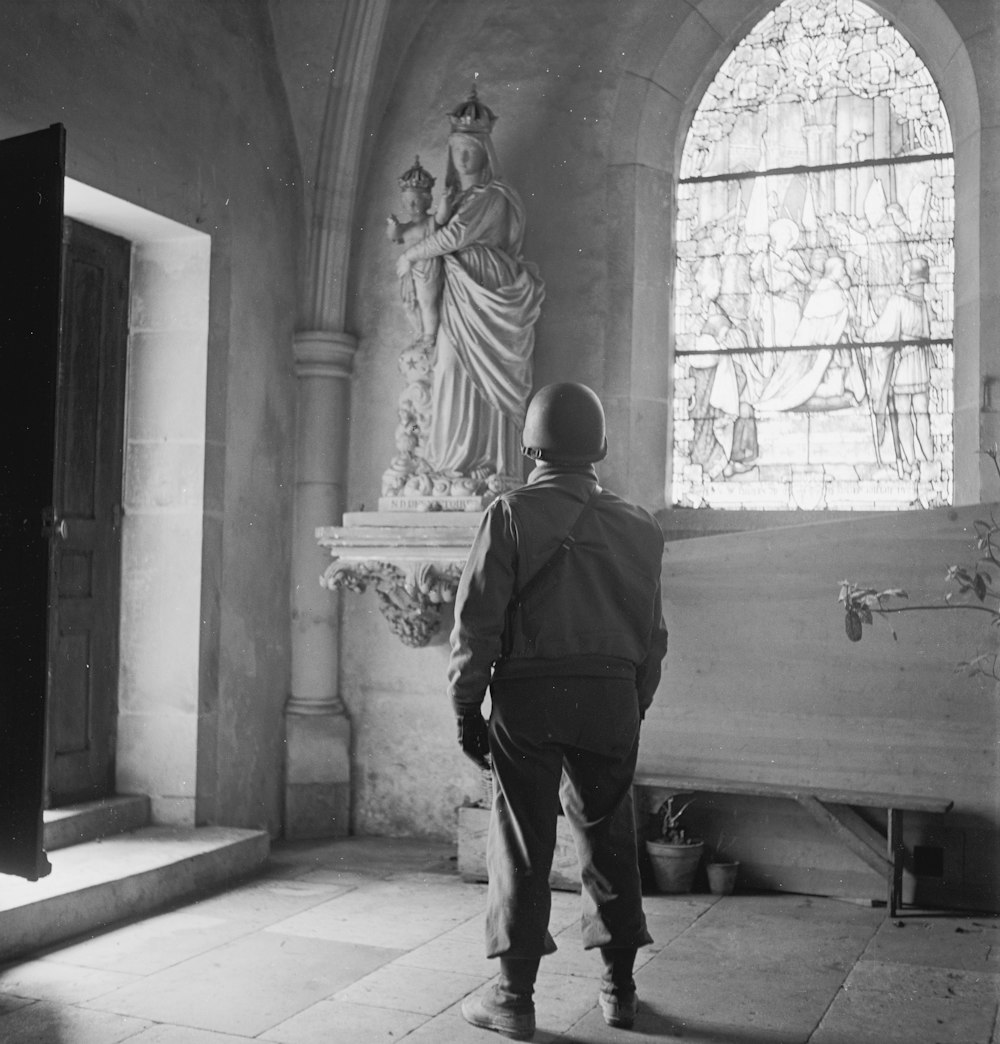 Soldier looking at a statue of the Madonna and Child in a church, probably in Europe during World War II