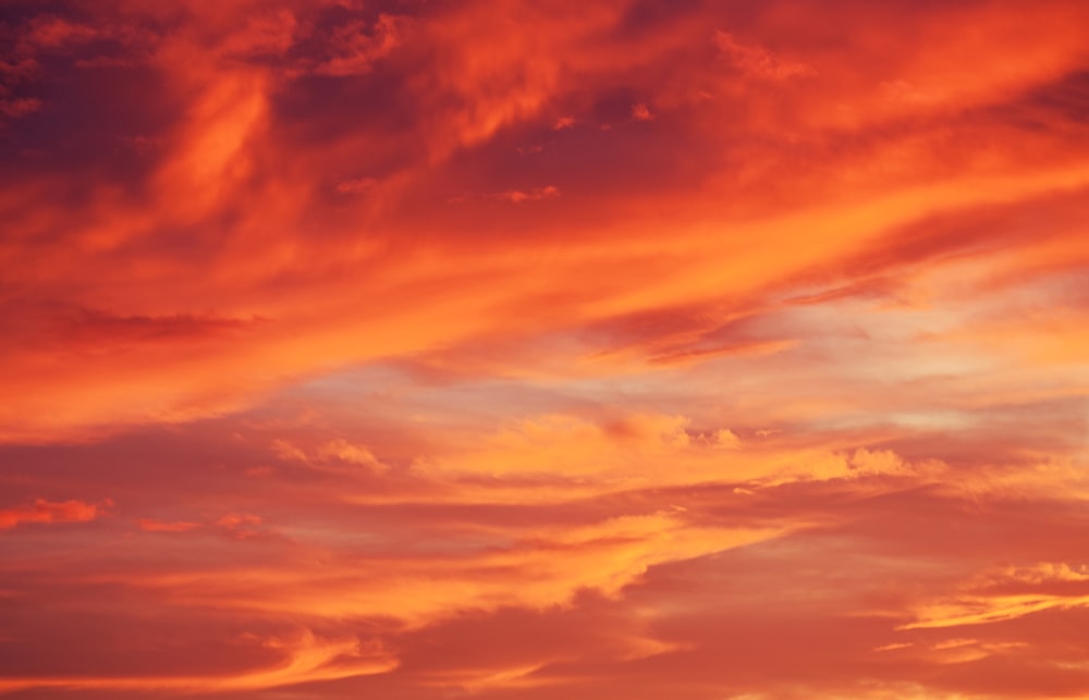 a plane flying in the sky at sunset