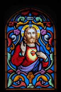 A close-up of a heartfelt stained glass window depicting a wounded heart symbolizing sacrifice and healing.