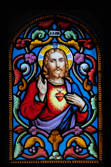 A close-up of a heartfelt stained glass window depicting a wounded heart symbolizing sacrifice and healing.