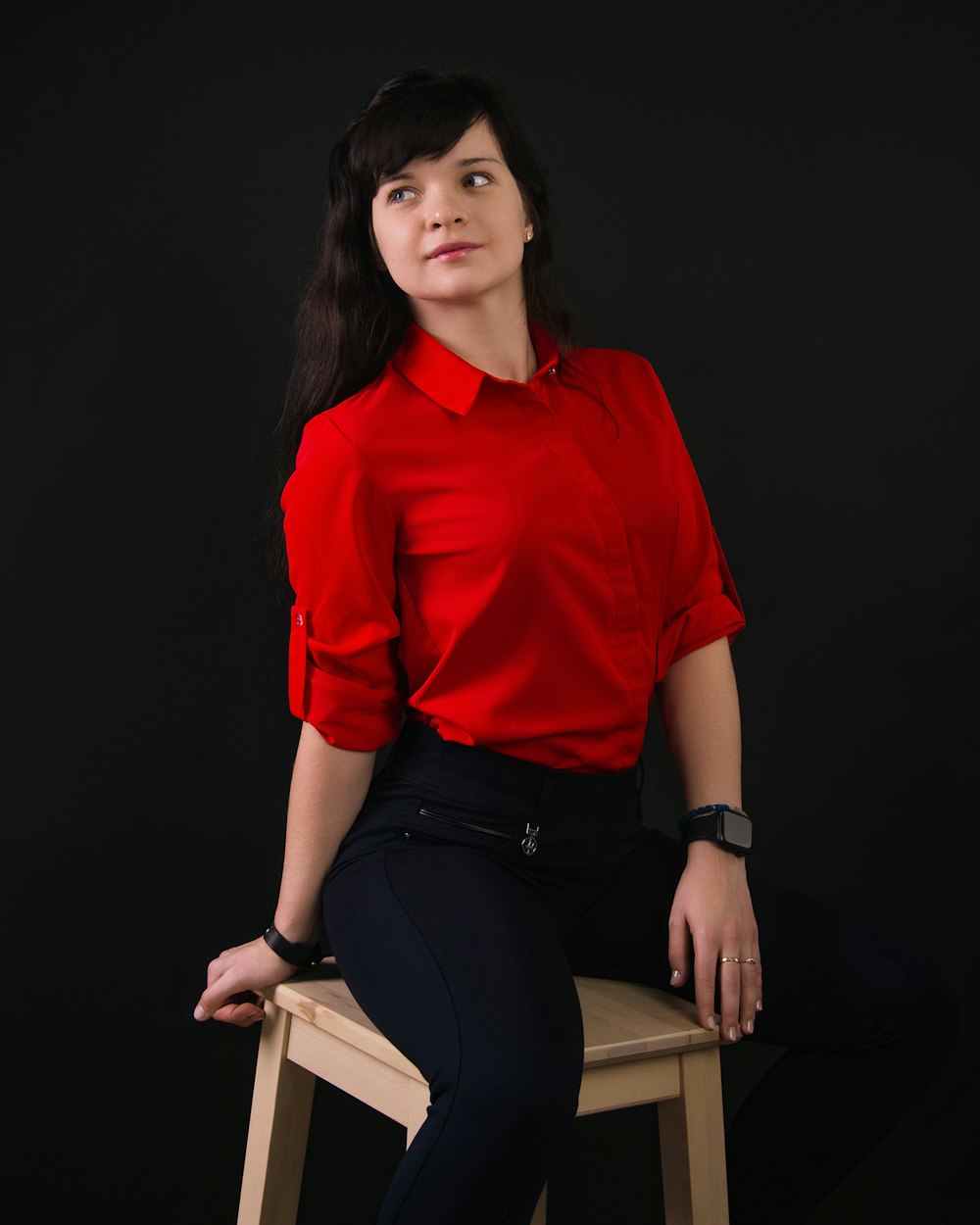 a woman in a red shirt is sitting on a stool