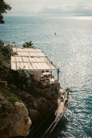 Sunny terrace view with rustic wooden tables and barrels set up for an aperitif by the Neptune beach.
