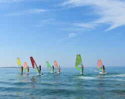 a group of people riding sail boards on top of a body of water