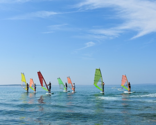 a group of people riding sail boards on top of a body of water