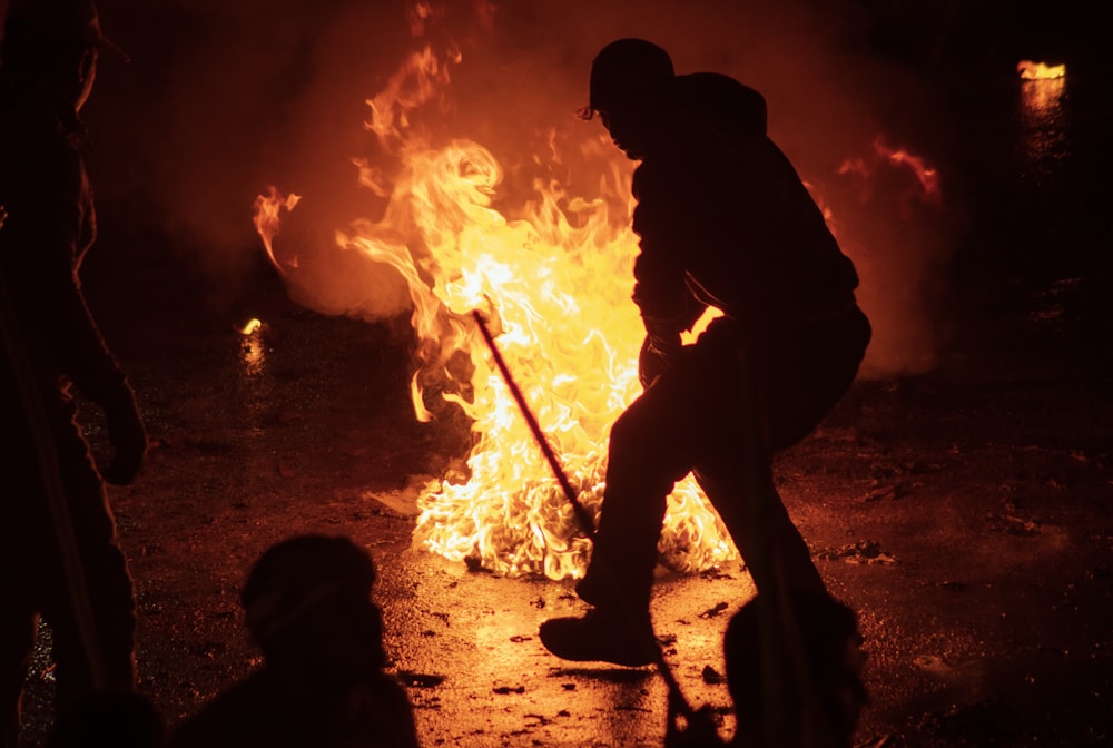 a man with a broom standing in front of a fire