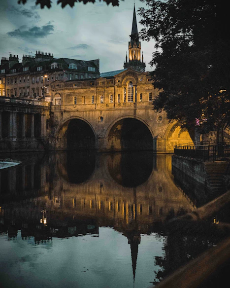 a bridge over a body of water with a clock tower in the background