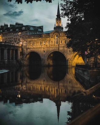 a bridge over a body of water with a clock tower in the background