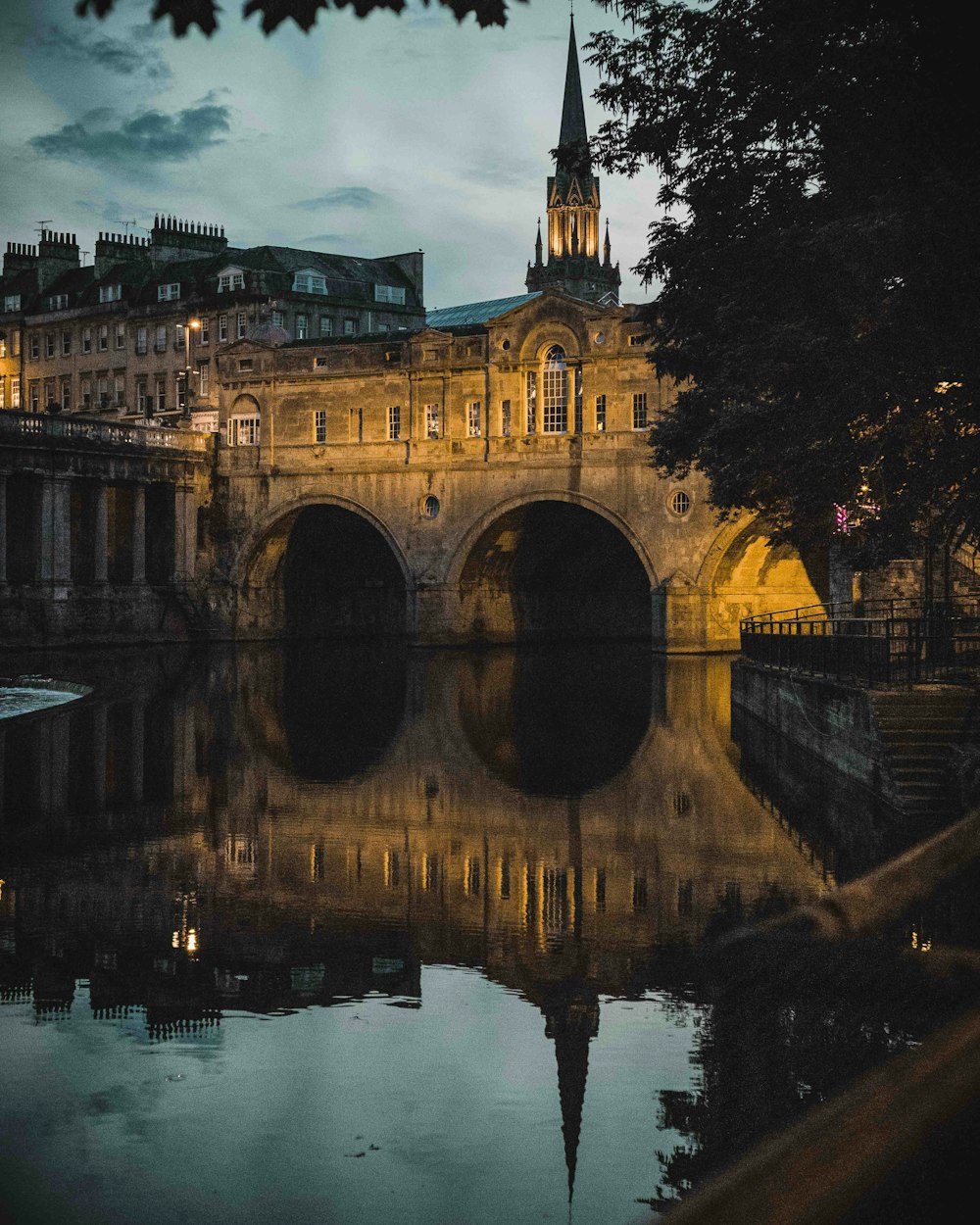 a bridge over a body of water with a clock tower in the background