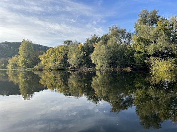 A peaceful lakeside scene with reflections of trees and sky.