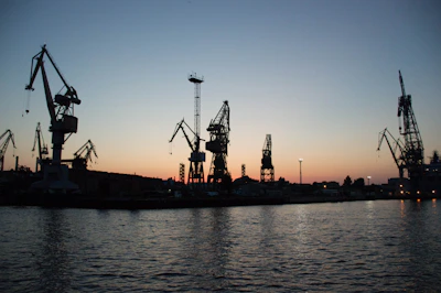 Evening scene showing cranes silhouetted against the sky as they complete a complex lift.