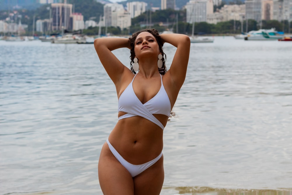 eine Frau im weißen Bikini steht am Strand