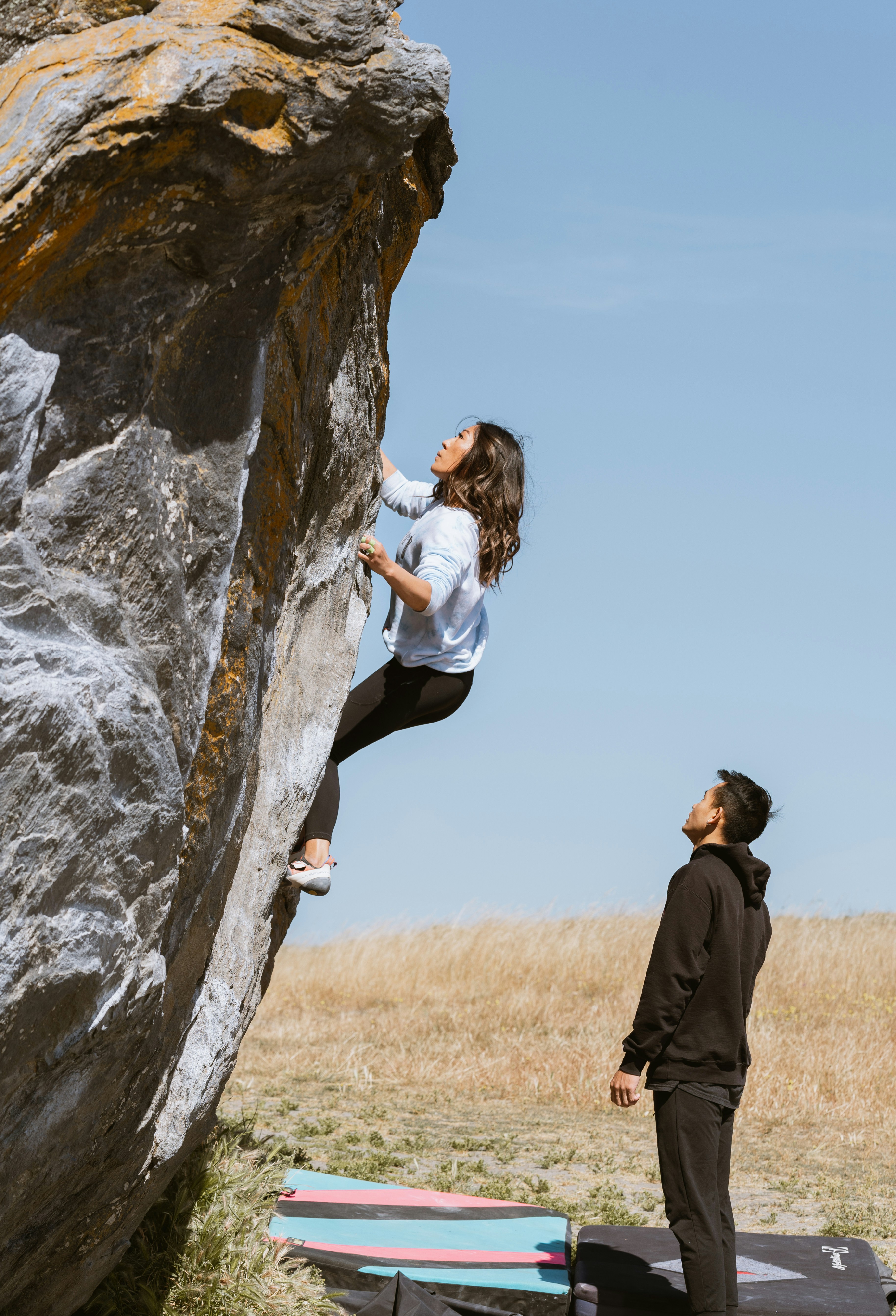 a man standing next to a woman on top of a rock