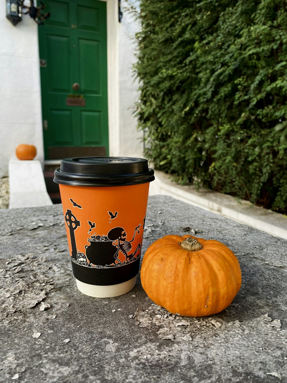 a cup of coffee sitting next to a pumpkin