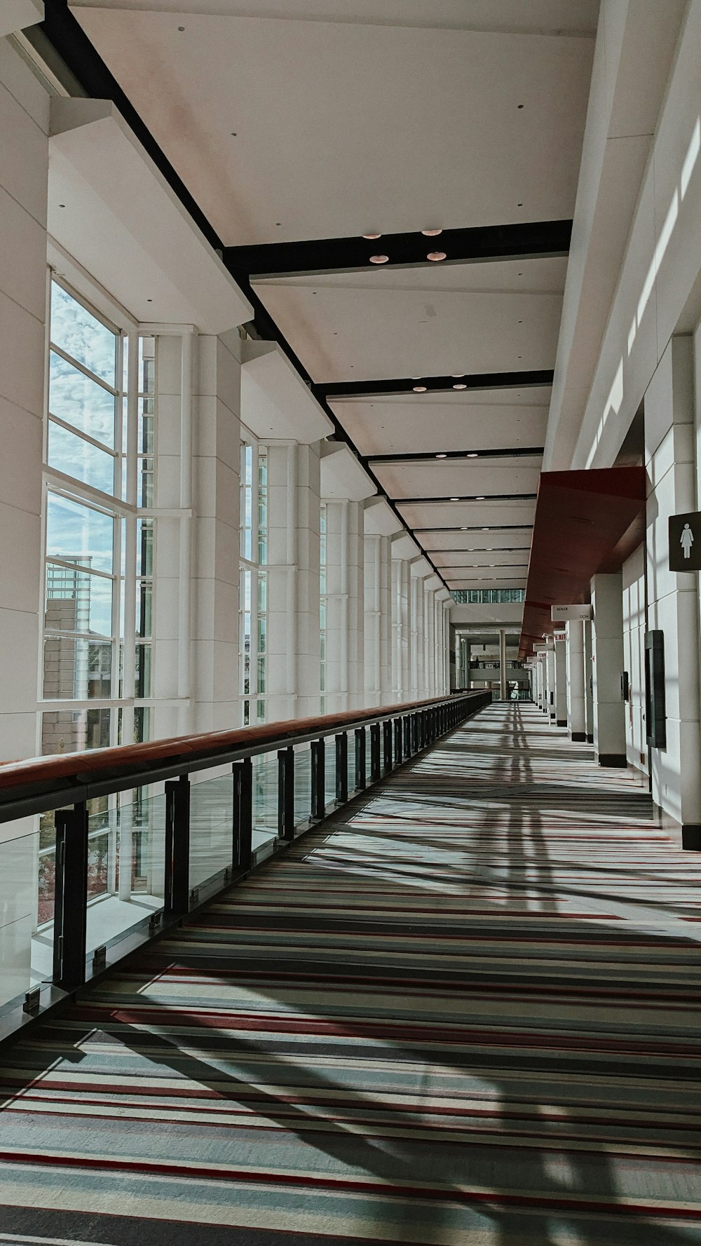 a long hallway with many windows and a striped carpet