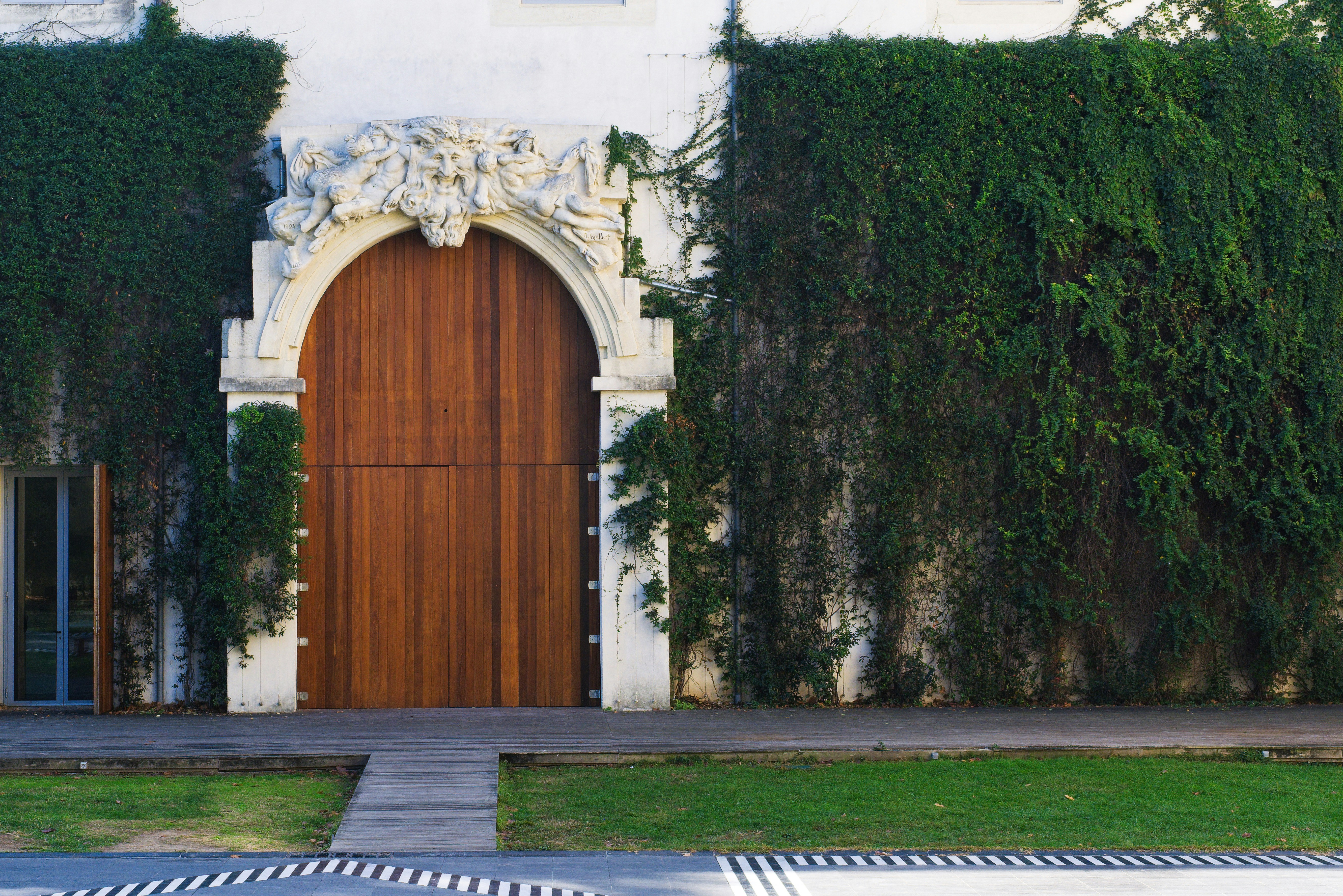 une grande porte en bois assise à côté d’un mur vert luxuriant