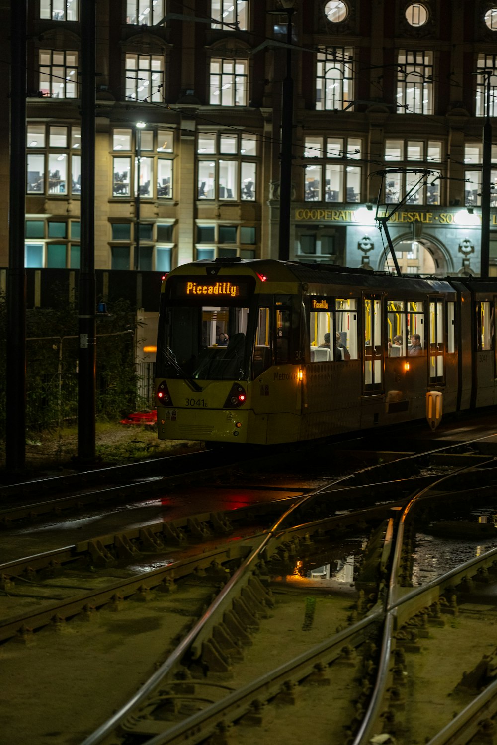 a trolley on tracks in front of a building at night