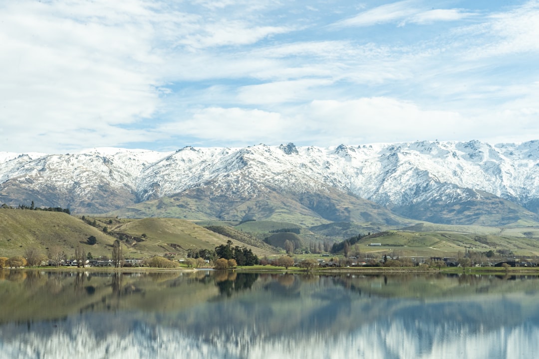 a lake with mountains in the background, View of snowy Mt Pisa and its reflection on Clutha River/Mata-Au (Lake Dunstan)