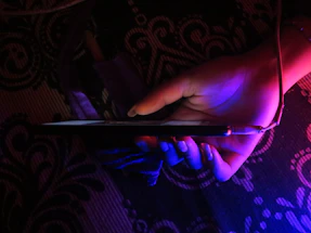 A friendly customer service representative holding a smartphone with a glowing blue and violet background.
