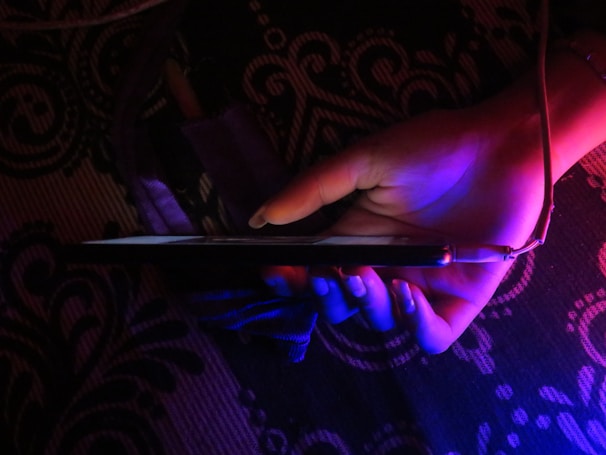 Close-up of a hand holding a smartphone with a colorful mobile design background