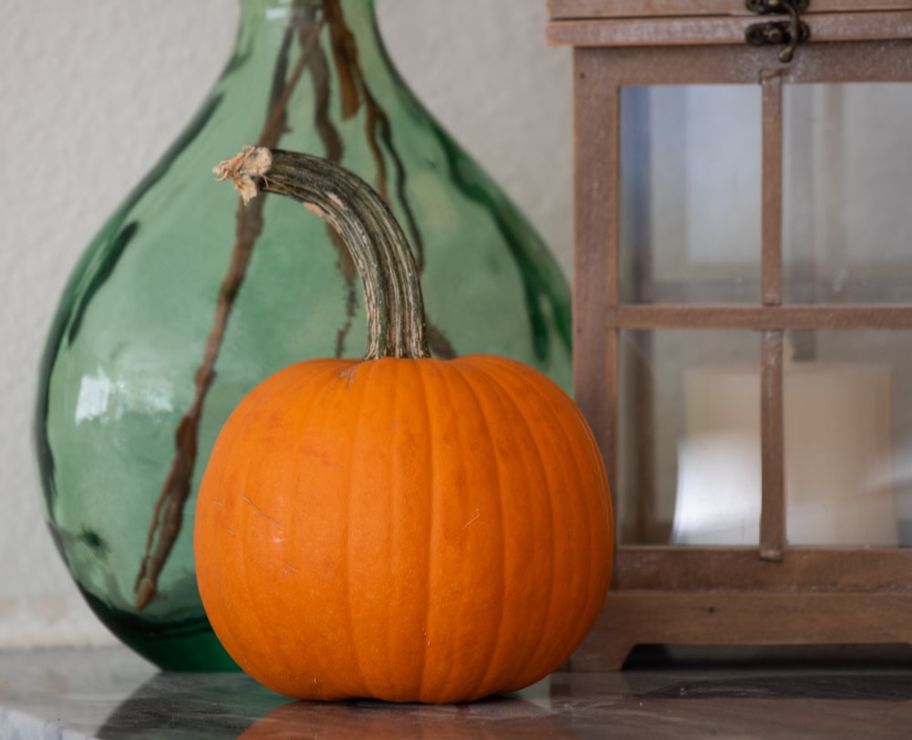 a pumpkin sitting on a table next to a vase