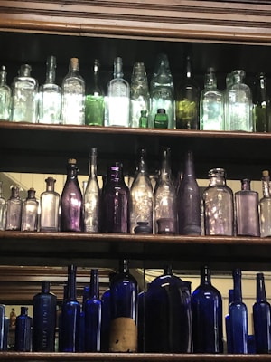 A collection of colorful antique glassware arranged neatly on a weathered shelf.