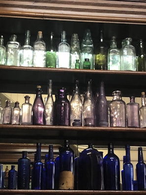 A collection of colorful vintage glass bottles on a shelf.