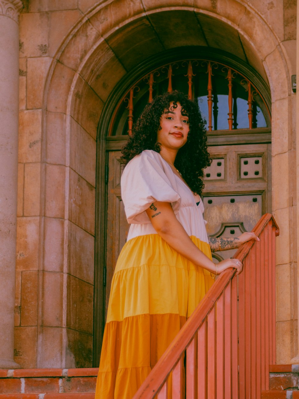 a woman in a yellow and white dress standing on a stair case
