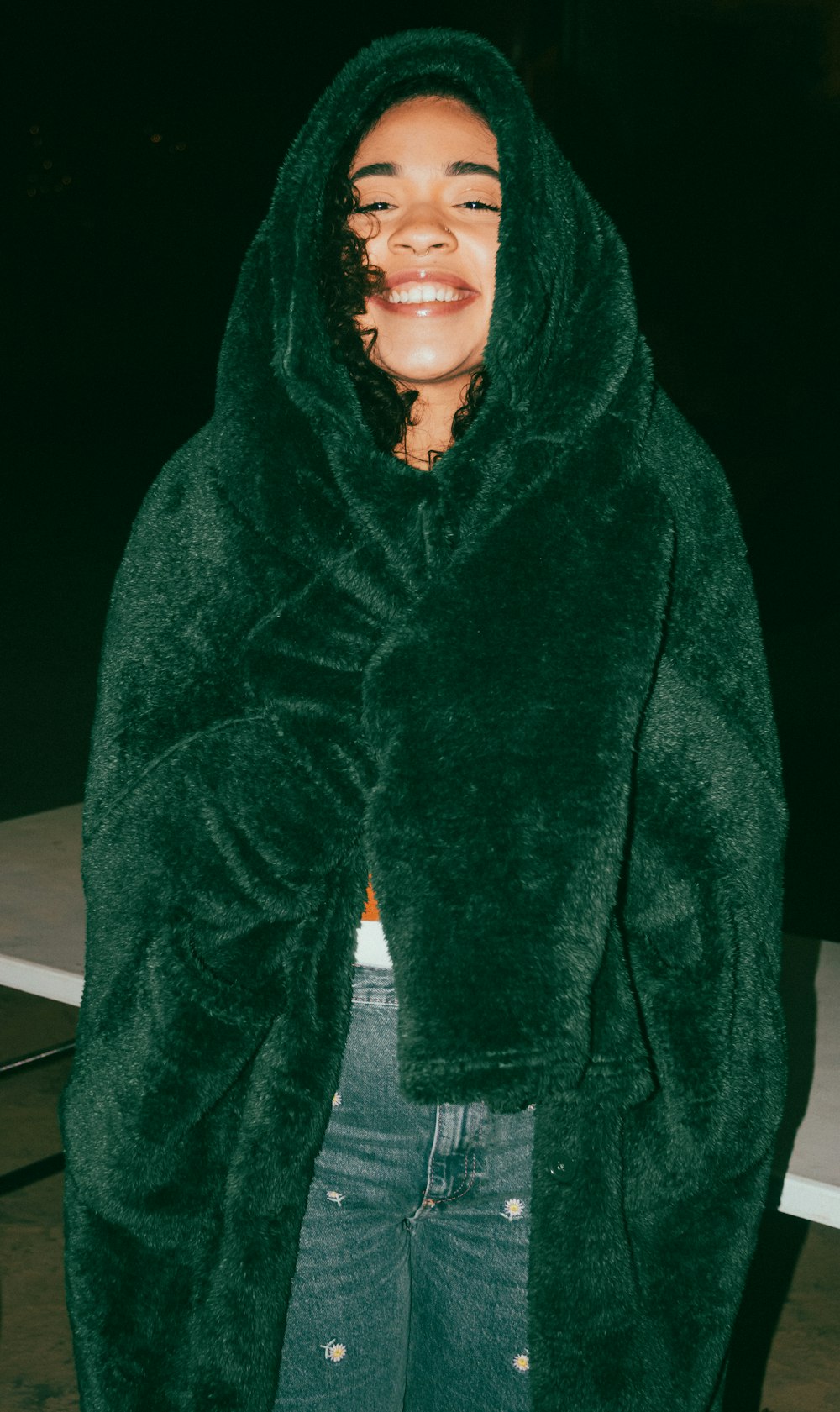 a woman wearing a green hooded jacket and jeans