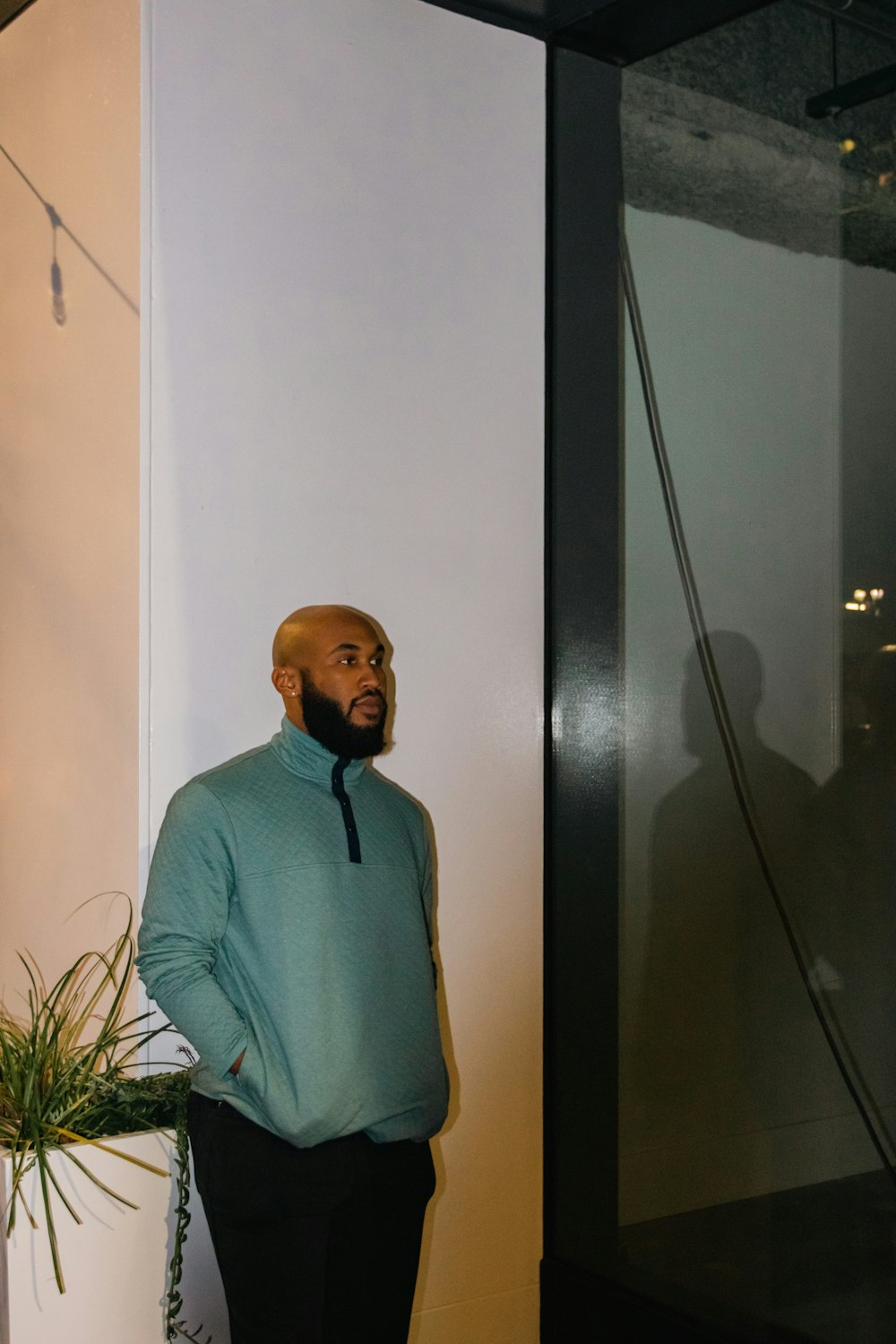 a man standing next to a plant in a room