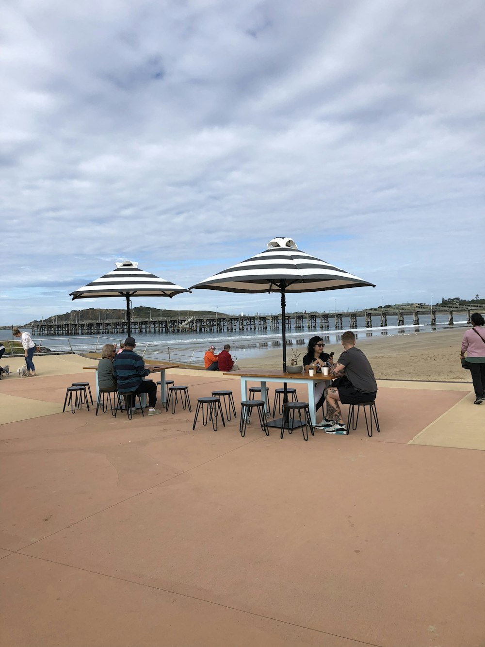 a group of people sitting at tables under umbrellas