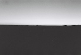 A minimalist and monochrome landscape with a horizon line that separates the dark foreground from the lighter sky.
