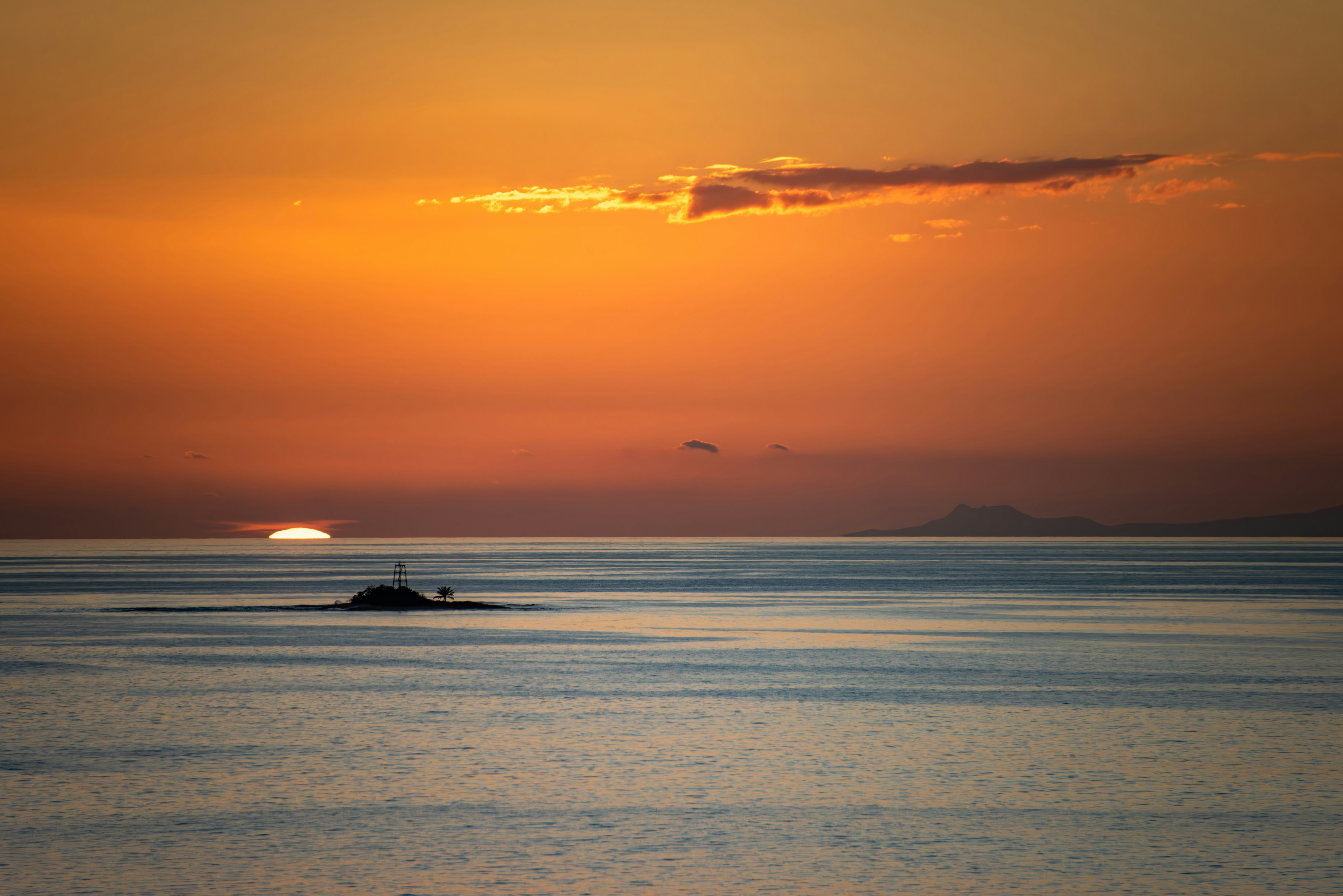 the sun is setting over the ocean with a boat in the water, ‎⁨Antigua and Barbuda⁩, ⁨Saint John’s Harbour⁩ at sunset. Nikon D810 300mm.