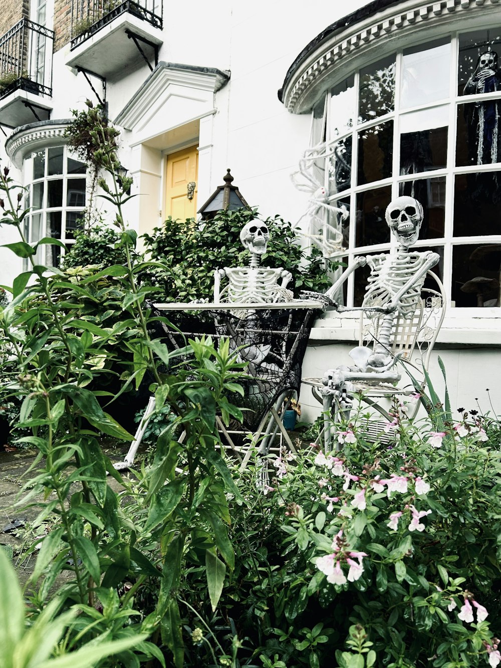 a skeleton sitting at a table in a garden
