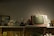 A vintage scene featuring an old-fashioned television with antennas sits prominently on a shelf, surrounded by various retro items. These include an analog clock, a classic camera, framed pictures, and decorative plates. The warm lighting casts a nostalgic ambiance over the assemblage.