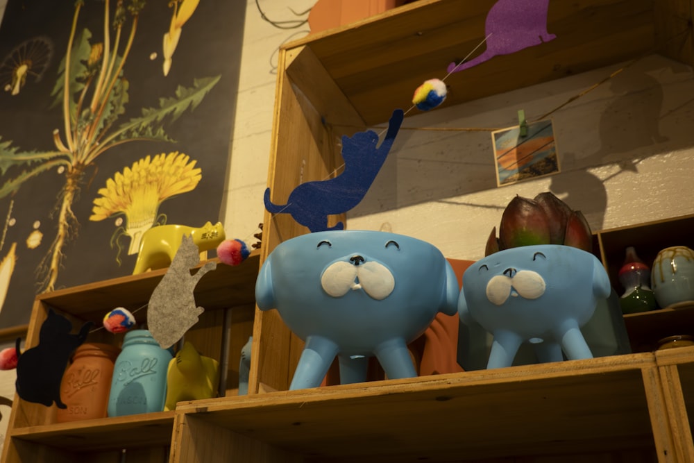 a couple of blue elephants sitting on top of a wooden shelf
