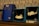 Several jewelry items are displayed on a wooden surface. There are two blue boxes with necklaces featuring cat-shaped pendants. One of the pendants depicts a cat wearing a small hat, while the other depicts a cat with a red bow. Next to these is another blue box featuring a pair of 24K gold plated earrings shaped like cat faces, priced at $89. The background consists of a patterned wall with stylized designs.
