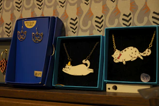 Close-up of delicate cat-themed jewelry and accessories arranged on a vintage velvet cloth.