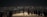 Groups of people stand on an illuminated platform overlooking a sprawling cityscape at night, with countless lights twinkling across the horizon.