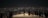 Groups of people stand on an illuminated platform overlooking a sprawling cityscape at night, with countless lights twinkling across the horizon.