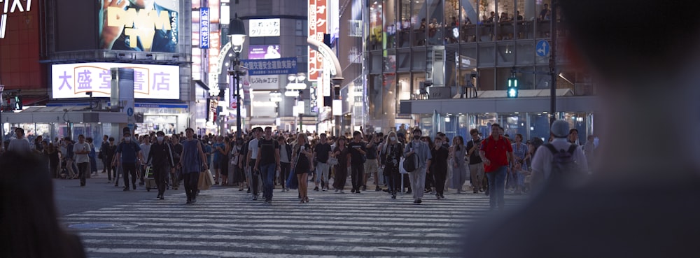 a crowd of people walking across a street at night