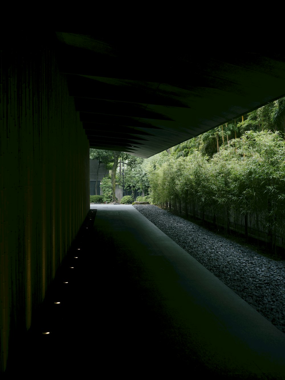 a dark tunnel with a walkway between two buildings