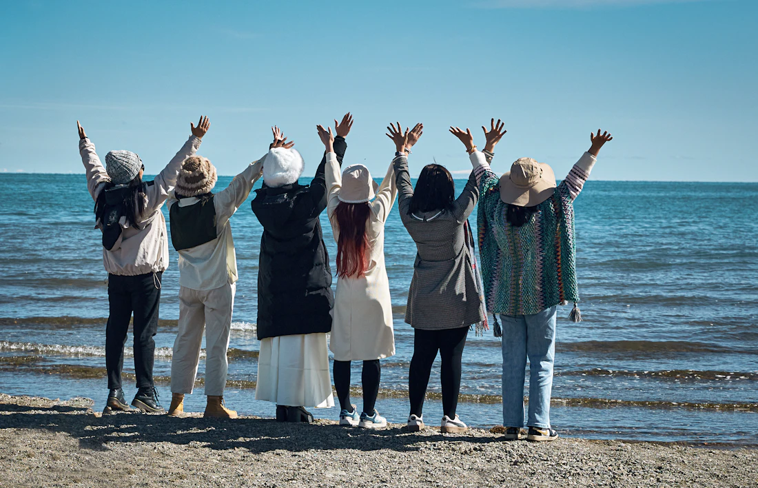 A joyful group of women with arms raised on the beach