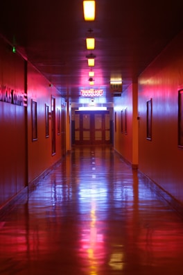The hallway’s VCT floor shining brightly after our refinishing work, reflecting overhead lights.