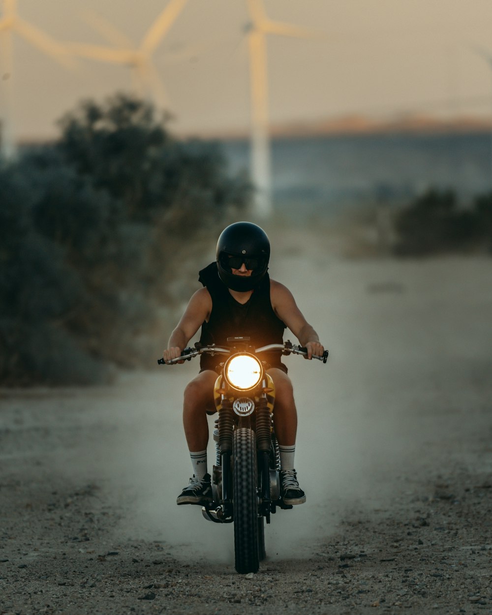 a man riding a motorcycle down a dirt road