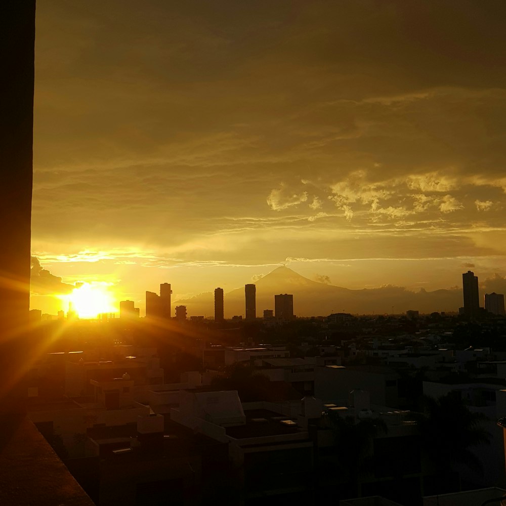 the sun is setting over a city with tall buildings