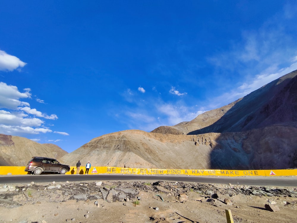 a black car driving down a road next to mountains